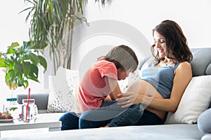 Young pregnant woman, reading a book at home to her boy