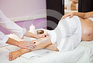 Young pregnant woman relaxing with hand leg massage at beauty sp