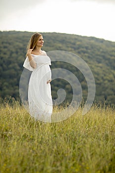 Young pregnant woman relaxing outside in nature