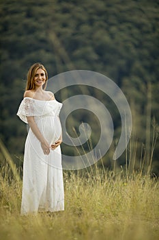 Young pregnant woman relaxing outside in nature