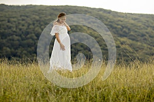 Young pregnant woman relaxing outside in nature