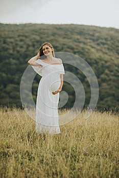 Young pregnant woman relaxing outside in nature