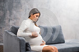 Young pregnant woman is resting at home and expecting a baby. Pregnancy, motherhood, health care and lifestyle concept.