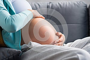 Young pregnant woman is resting at home and expecting a baby. Pregnancy, motherhood, health care and lifestyle concept.