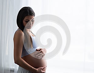 Young pregnant woman is resting at home and expecting a baby. Pregnancy, motherhood, health care and lifestyle concept.