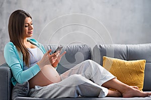 Young pregnant woman is resting at home and expecting a baby. Pregnancy, motherhood, health care and lifestyle concept.