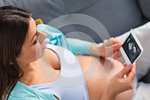 Young pregnant woman is resting at home and expecting a baby. Pregnancy, motherhood, health care and lifestyle concept.