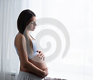 Young pregnant woman is resting at home and expecting a baby. Pregnancy, motherhood, health care and lifestyle concept.