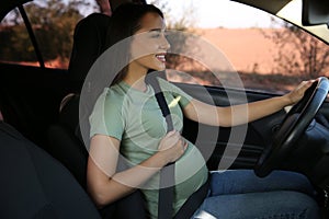 Young pregnant woman with safety belt in car