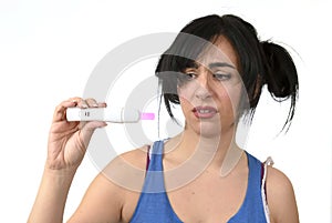 Young pregnant woman scared in shock checking pink positive result on pregnancy test