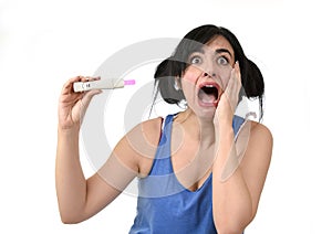 Young pregnant woman scared in shock checking pink positive result on pregnancy test