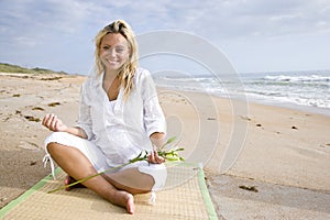 Young pregnant woman sitting on beach