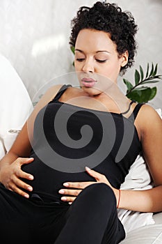 Young pregnant woman sitting on sofa