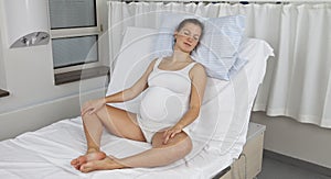 Young pregnant woman sitting upright on delivery bed