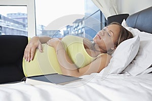 Young pregnant woman sleeping on bed at home