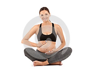 Young pregnant woman in sportswear on white background