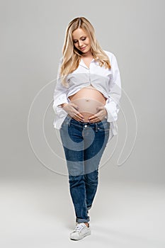 Young pregnant woman in studio. Beautiful stomach. Pregnancy, childbearding and new life concept.