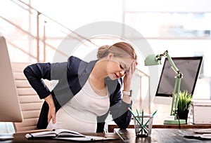 Young pregnant woman suffering from pain while working