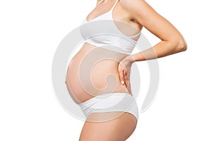 Young pregnant woman in swimsuit. Girl expecting a baby and touching her belly isolated on white background. Close-up