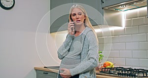 Young pregnant woman talking to her husband using phone at home. The pregnant girl communicates