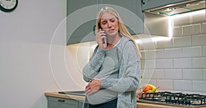 Young pregnant woman talking to her husband using phone at home. The pregnant girl communicates