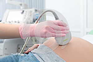 Young pregnant woman undergoing ultrasound scan in clinic, closeup view