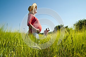 Young pregnant woman waiting her man in the wheat field.