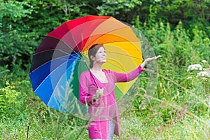 Young pregnant woman walking under colorful umbrella