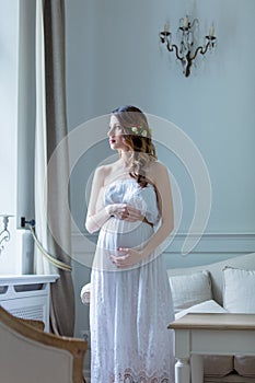 Young pregnant woman in white dress