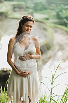 Young pregnant woman in white dress. Harmony with nature. Pregnancy concept.