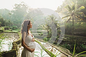 Young pregnant woman in white dress. Harmony with nature. Pregnancy concept.