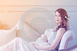 Young pregnant woman in white dress sitting