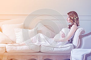 Young pregnant woman in white dress sitting