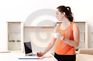 The young pregnant woman working at home