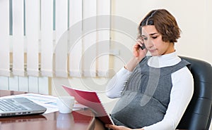 Young pregnant woman working at office