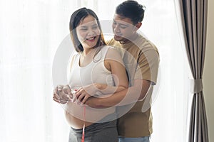 Young pregnant woman measuring belly centimeter, healthcare and pregnancy care