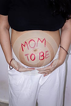 Young pregnant women showing her round belly womb with message mom to be from different angle