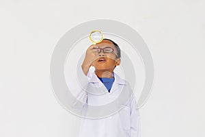 Young preteen African American kid wearing lab coat looking up with magnifier