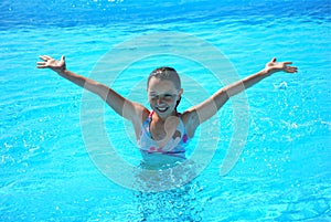 Young preteen girl in pool with arms in a V shape