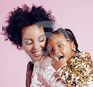 Young pretty african-american mother with little cute daughter hugging, happy smiling on pink background, lifestyle