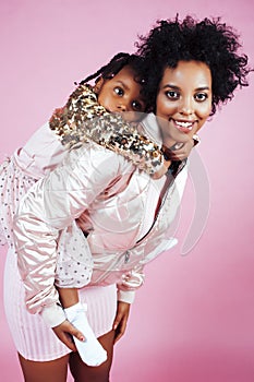 Young pretty african-american mother with little cute daughter hugging, happy smiling on pink background, lifestyle