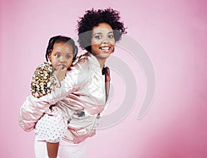 Young pretty african-american mother with little cute daughter hugging, happy smiling on pink background, lifestyle