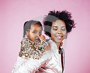 Young pretty african-american mother with little cute daughter hugging, happy smiling on pink background, lifestyle