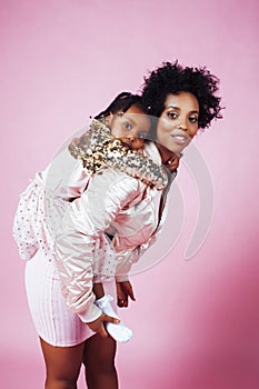 Young pretty african-american mother with little cute daughter hugging, happy smiling on pink background, lifestyle