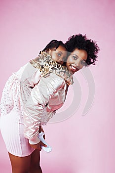 Young pretty african-american mother with little cute daughter hugging, happy smiling on pink background, lifestyle