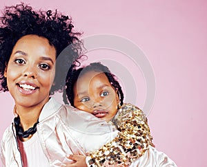 Young pretty african-american mother with little cute daughter hugging, happy smiling on pink background, lifestyle