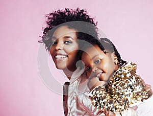 Young pretty african-american mother with little cute daughter hugging, happy smiling on pink background, lifestyle