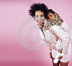 Young pretty african-american mother with little cute daughter hugging, happy smiling on pink background, lifestyle