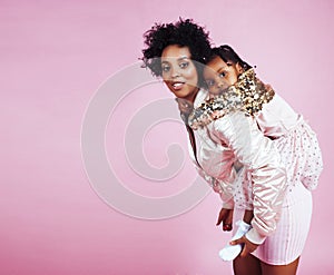 Young pretty african-american mother with little cute daughter hugging, happy smiling on pink background, lifestyle