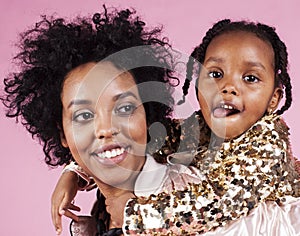 young pretty african-american mother with little cute daughter hugging, happy smiling on pink background, lifestyle